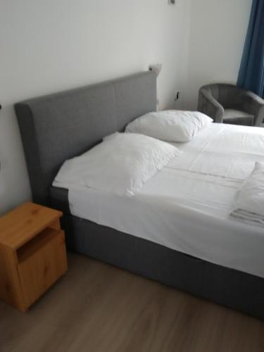 a bed with white sheets and a night stand in a room at Paprika vendégház in Harkány