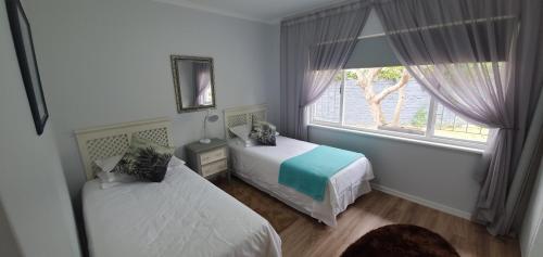 a bedroom with two beds and a window at Fredericks in Plettenberg Bay