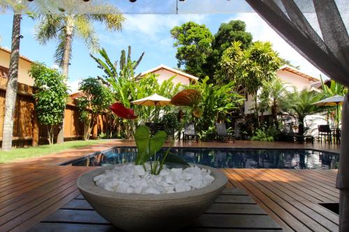 a courtyard with a pool and a bowl with flowers at Pousada Cheiro Verde in Arraial d'Ajuda