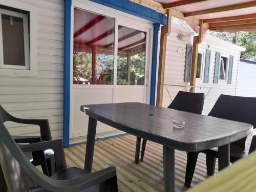 - une table et des chaises sur la terrasse couverte d'une maison dans l'établissement Camping le Chêne, à Tallard