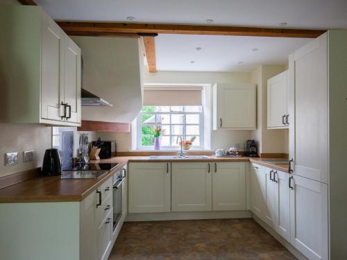 Una cocina con gabinetes blancos y una ventana. en Prince Rupert, en Winchcombe