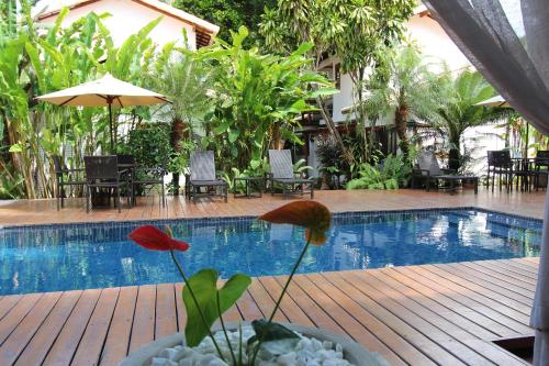 a swimming pool with a table and chairs and an umbrella at Pousada Cheiro Verde in Arraial d'Ajuda
