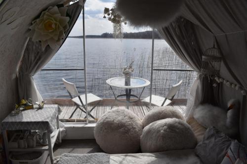 een kamer met een balkon met uitzicht op het water bij Gulbju māja - Swan house in Usma