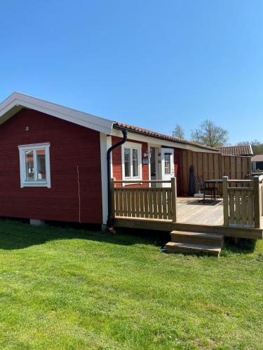 a house with a large wooden deck in the yard at Talluddens Stugby in Färjestaden