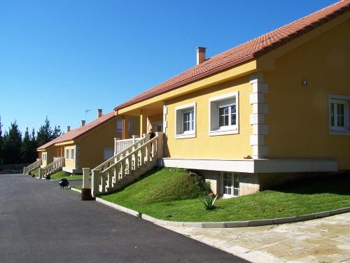 a yellow house with a white railing next to a street at Apartamentos Turísticos San Breixo in Carballo