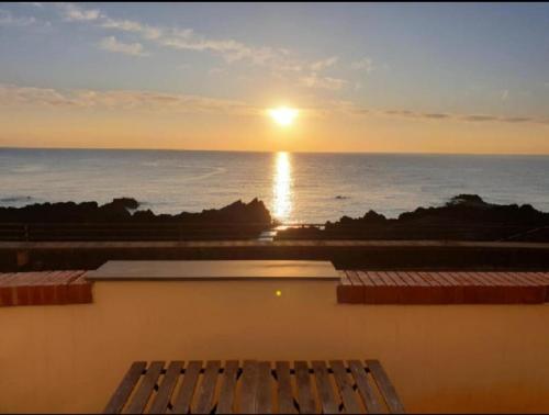 a sunset over the ocean from a building with a bench at A casa di Edo in Acireale