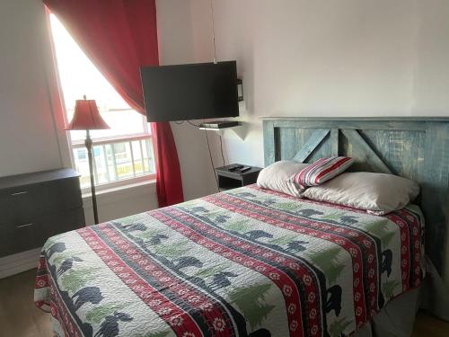 a bedroom with a bed with a colorful blanket and a window at Gestion clin d’œil - 501 in La Tuque