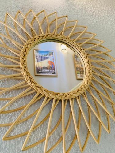 a large rattan mirror with a sunburst design on a wall at Hôtel Le Petit Castel in Antibes