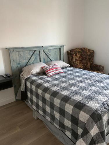 a bedroom with a bed with a checkered blanket and a chair at Gestion clin d'oeil - 503 in La Tuque