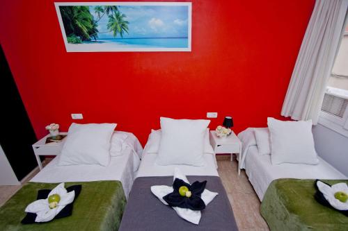 a room with two beds and a red wall at Barcelona City North Hostal in Barcelona