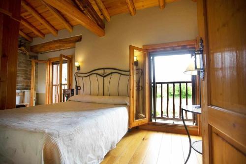 a bedroom with a large bed and a balcony at El Corral de Villacampa in Mondot