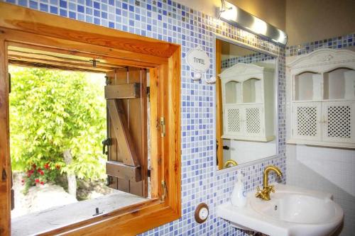 une salle de bain avec un lavabo, un miroir et une fenêtre dans l'établissement El Corral de Villacampa, à Mondot