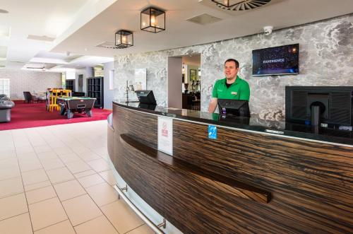 a man standing at a bar in a hotel lobby at ibis Styles Crewe in Crewe