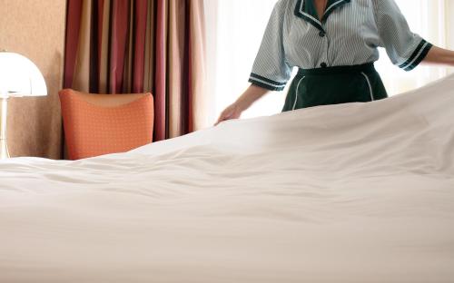 a woman is standing next to a bed at Holiday Inn Athens Attica Av, Airport W. by IHG in Athens