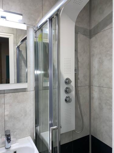 W łazience znajduje się prysznic, umywalka i lustro. w obiekcie Aero Hotel w mieście Issy-les-Moulineaux