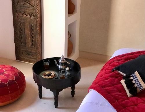a table with a bowl of food on it next to a bed at Riad Zahir in Marrakech