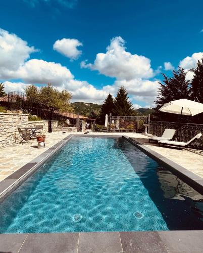 a swimming pool with two chairs and an umbrella at Agriturismo Poderi Zunino in Ponti