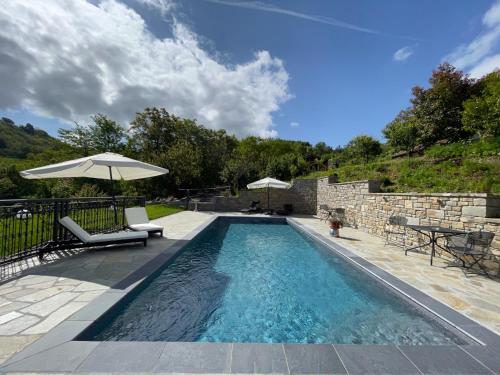 a swimming pool with two chairs and an umbrella at Agriturismo Poderi Zunino in Ponti