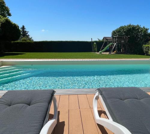 a pool with two lounge chairs and a playground at Panoráma Apartmanház in Balatonfüred