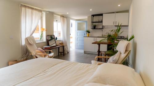 a bedroom with a bed and chairs and a kitchen at Pateo Estoril - Brand New Villa in Estoril in Estoril