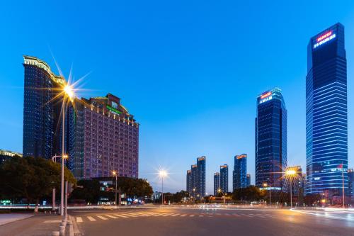 a city skyline with tall buildings and a street at night at Holiday Inn Express Suzhou Changjiang by IHG in Suzhou