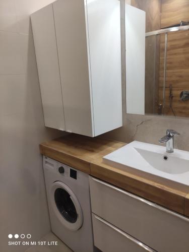 a bathroom with a sink and a washing machine at Perła Apartament Mińsk in Mińsk Mazowiecki
