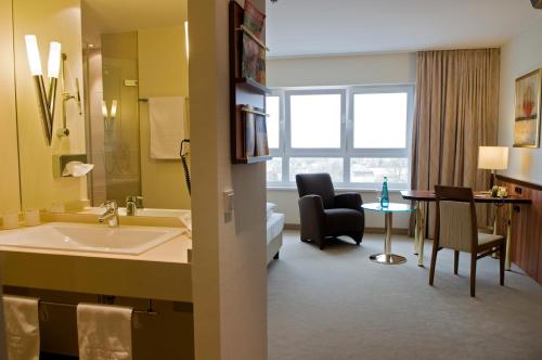 ein Hotelzimmer mit einem Bad mit einem Waschbecken und einem Sofa in der Unterkunft Ringhotel Katharinen Hof in Unna