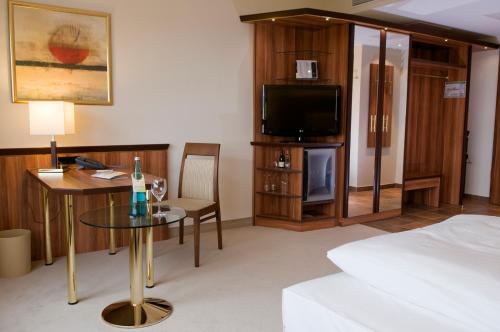 a hotel room with a bed and a table and a tv at Ringhotel Katharinen Hof in Unna