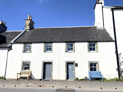 two benches in front of a white building at Newton Cottage South in Inveraray
