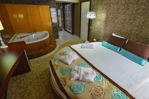 a bedroom with a tub and a bed with towels at Hotel Izgrev Spa & Aquapark in Struga