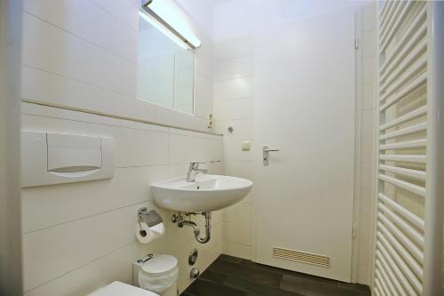 a white bathroom with a sink and a toilet at Dünenblick Wohnung 36 in Boltenhagen