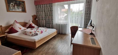 a bedroom with a bed and a desk with a laptop at Gästehaus-Pension Keiss in Hopferau