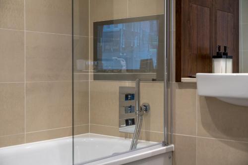 a shower with a glass door next to a sink at Luxurious Spacious 2Bed Suites Skyline River Views by Canary Wharf in London