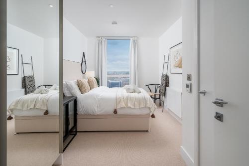 a white bedroom with a bed and a mirror at Luxurious Spacious 2Bed Suites Skyline River Views by Canary Wharf in London