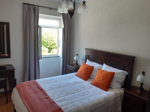 ein Schlafzimmer mit einem Bett mit orangefarbenen Kissen und einem Fenster in der Unterkunft Casa Araci in Vieira do Minho