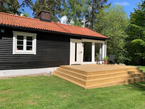 a house with a wooden deck in the yard at Skogshöjda in Tjörnarp