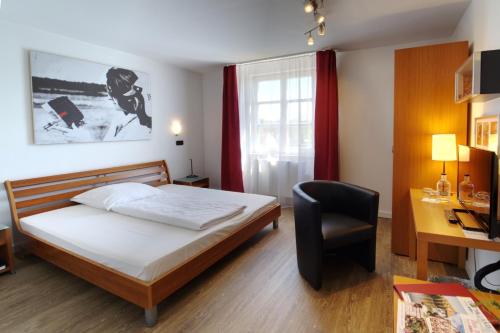 a bedroom with a bed and a desk and a chair at Hotel Reinhardts in Bietigheim-Bissingen