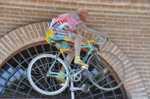 a man sitting on a bike against a brick wall at Hotel Jole in Cesenatico