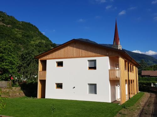 a white building with a brown roof and a church at Lahnhof in Lana