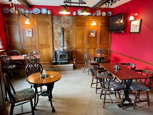 a restaurant with tables and chairs and a red wall at Plough and Harrow in Brecon