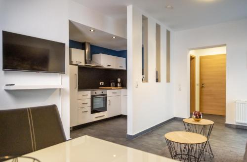 uma cozinha com armários brancos e uma mesa e cadeiras em Aparthotel Menden em Menden
