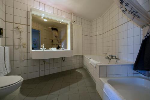 ein Badezimmer mit einem Waschbecken, einer Badewanne und einem WC in der Unterkunft Hotel Arcen in Arcen