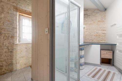 - une douche en verre dans une chambre dotée d'un mur en pierre dans l'établissement Maison Marceane, à Sainte-Marie de Ré