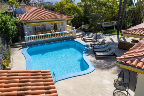 a swimming pool with chairs and a house at Balcón del Teide in La Orotava