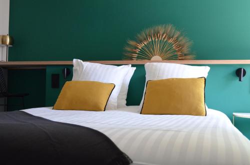 uma cama grande com lençóis brancos e almofadas amarelas em CHEZ FLO em Parentis-en-Born