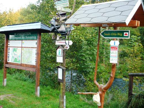 a sign in front of a bus stop with a statue at Meister BÄR HOTEL Frankenwald in Berg
