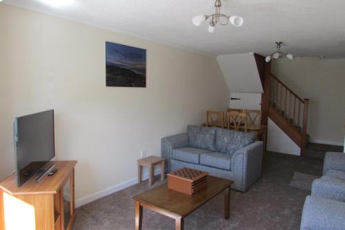 a living room with a couch and a tv at Clustiau'r Mor in Tywyn