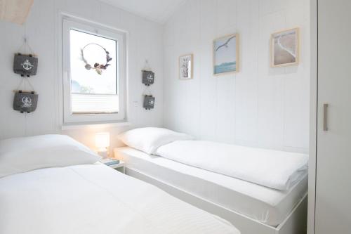2 camas en una habitación blanca con ventana en "Strandmuschel", en Dahme