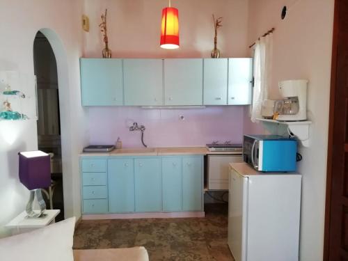 a kitchen with blue cabinets and a microwave at Seatinview Lodges in Mikonos