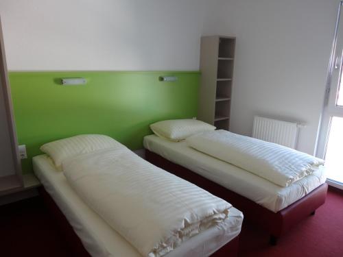 two beds in a room with a green wall at Hotel Wirt im Feld in Steyr